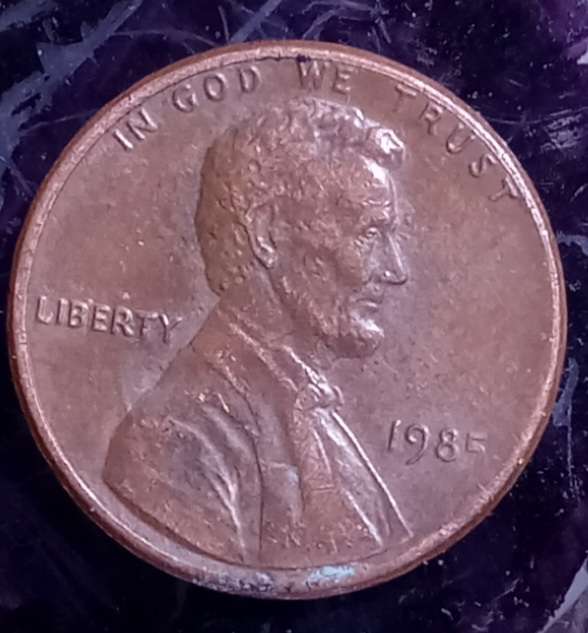 1985-P-1-Cent.-Struck-Through-Grease,-No-Rim-Near-Date.-Missing-Letters-On-Reverse.