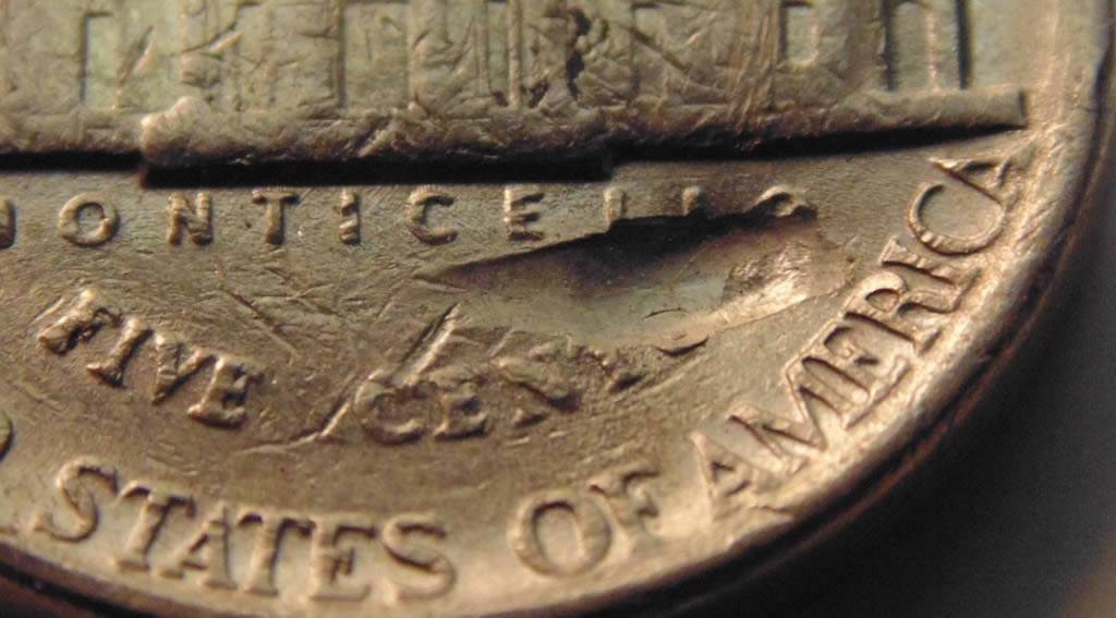 3-Nickels-With-Strange-Enough-Damage-To-Post.