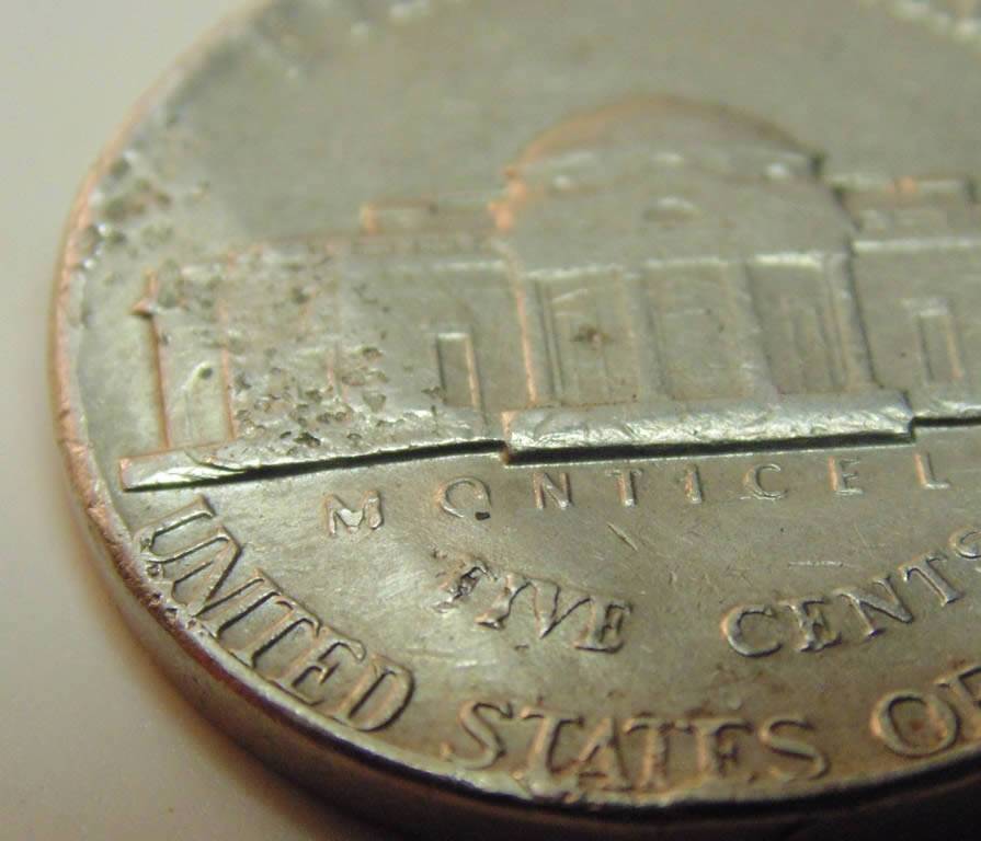 3-Nickels-With-Strange-Enough-Damage-To-Post.
